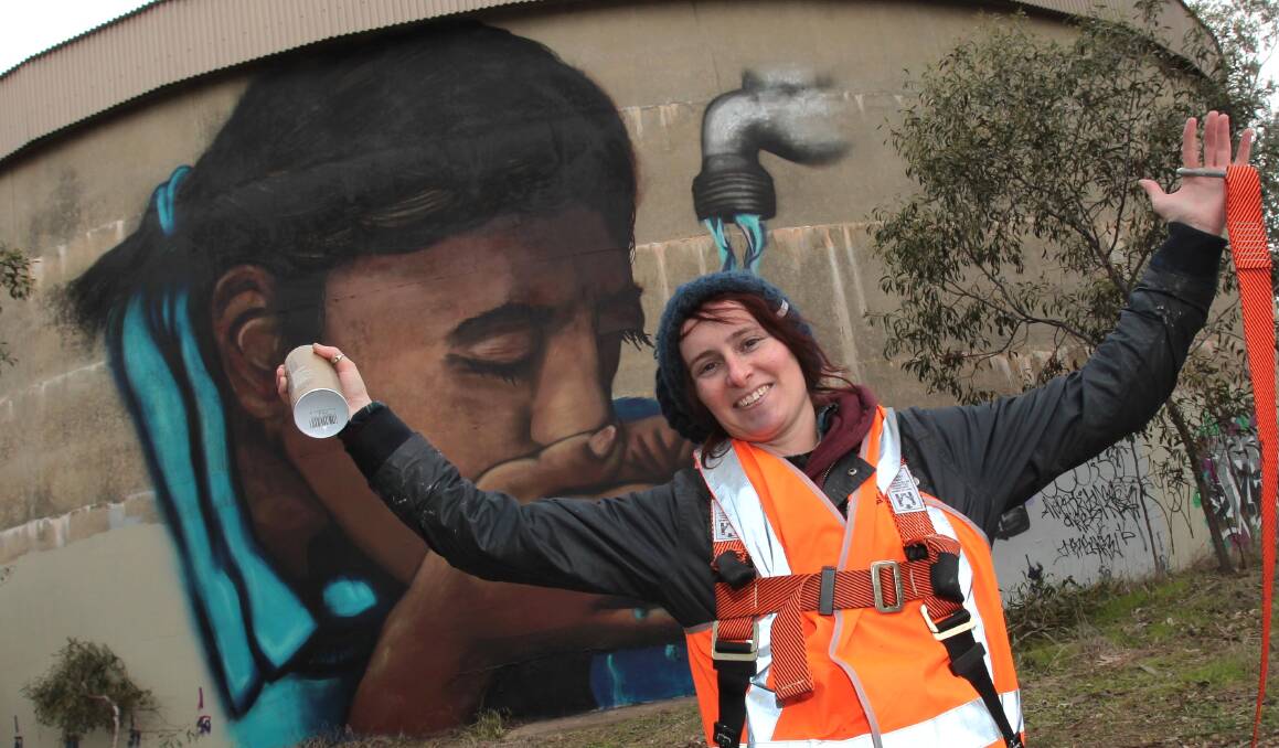 TANKS FOR THE OPPORTUNITY: Mural artist Trina Collins in front of one of the finished faces on Willans Hill. Picture: Les Smith