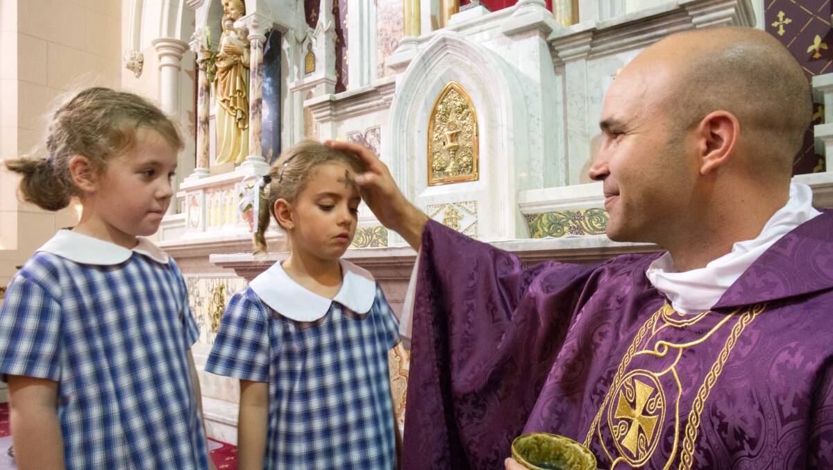 ASH WEDNESDAY: Fr Beltrame marks the forehead of five-year-old St Joseph's Primary School kindergarten pupil Livia Humphrey watched by classmate Mae Schiller.