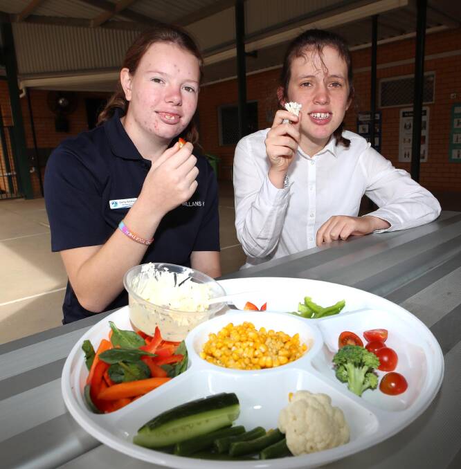 HUNGRY WORK: Emily Baldwin, 17, Maggie Standley, 15, enjoy a snack at the Great Veggie Crunch at Willans Hill School. Picture: Les Smith