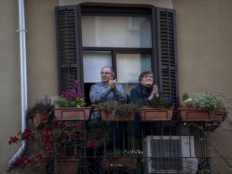 A couple applaud medical staff from their balcony in Barcelona.